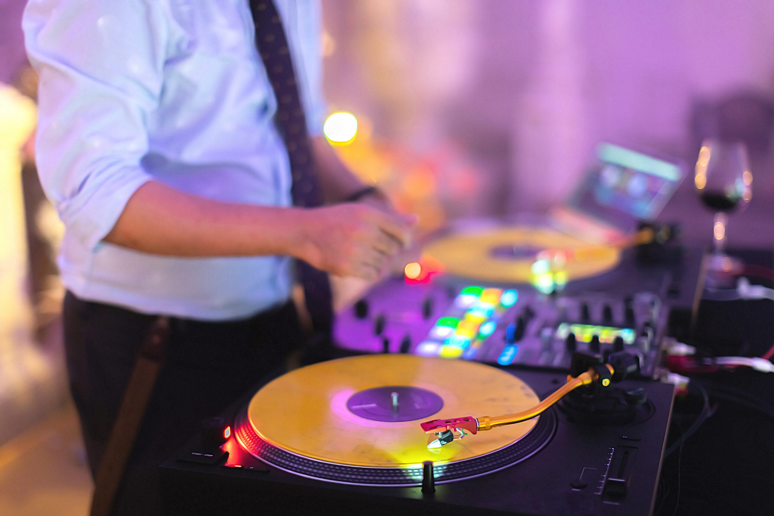 DJ mixing on turntables with colorful lighting