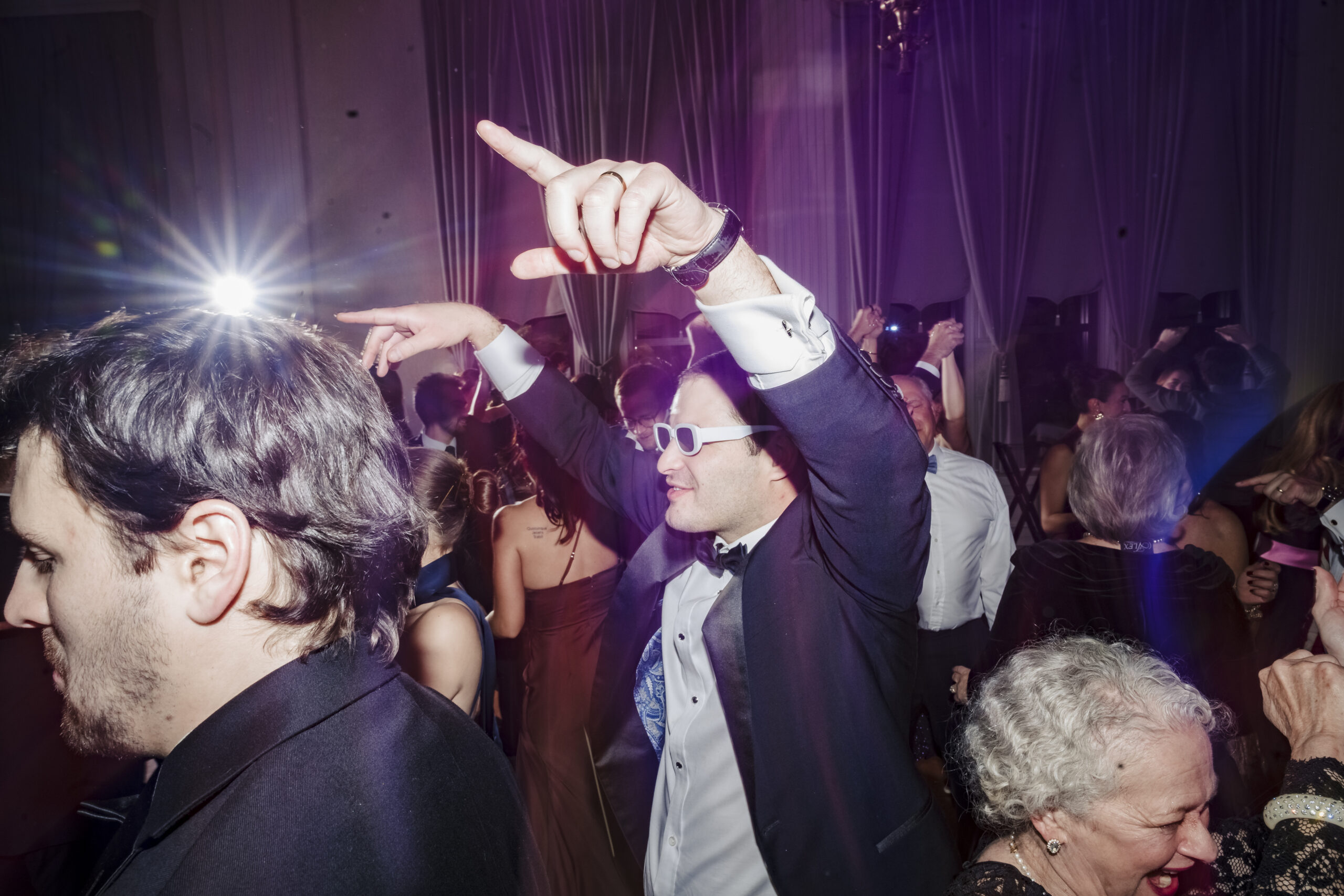 Wedding guests dancing under stage lighting
